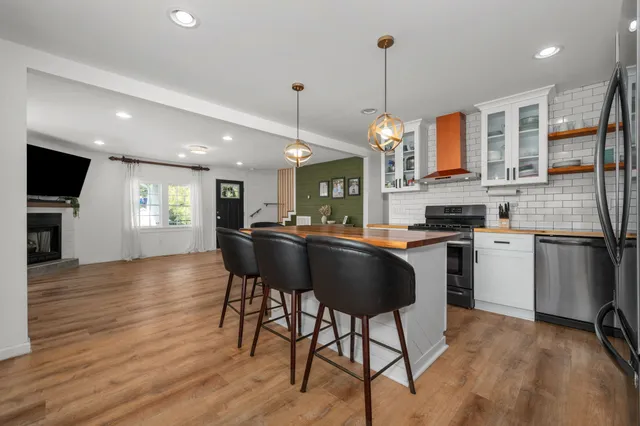 a kitchen with stainless steel appliances granite countertop a stove top oven a refrigerator a sink and a dining table with wooden floor