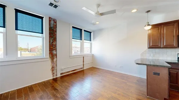 a view of an empty room with window and wooden floor