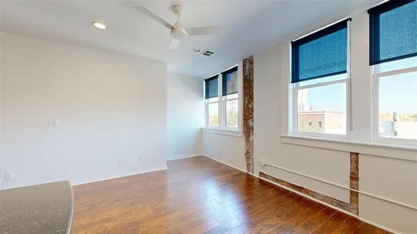 a view of an empty room with wooden floor and a window