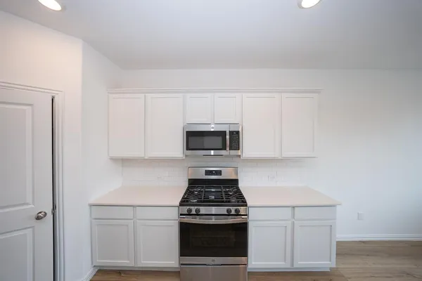 a kitchen with white cabinets and stainless steel appliances