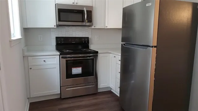 a kitchen with stainless steel appliances white cabinets and a refrigerator