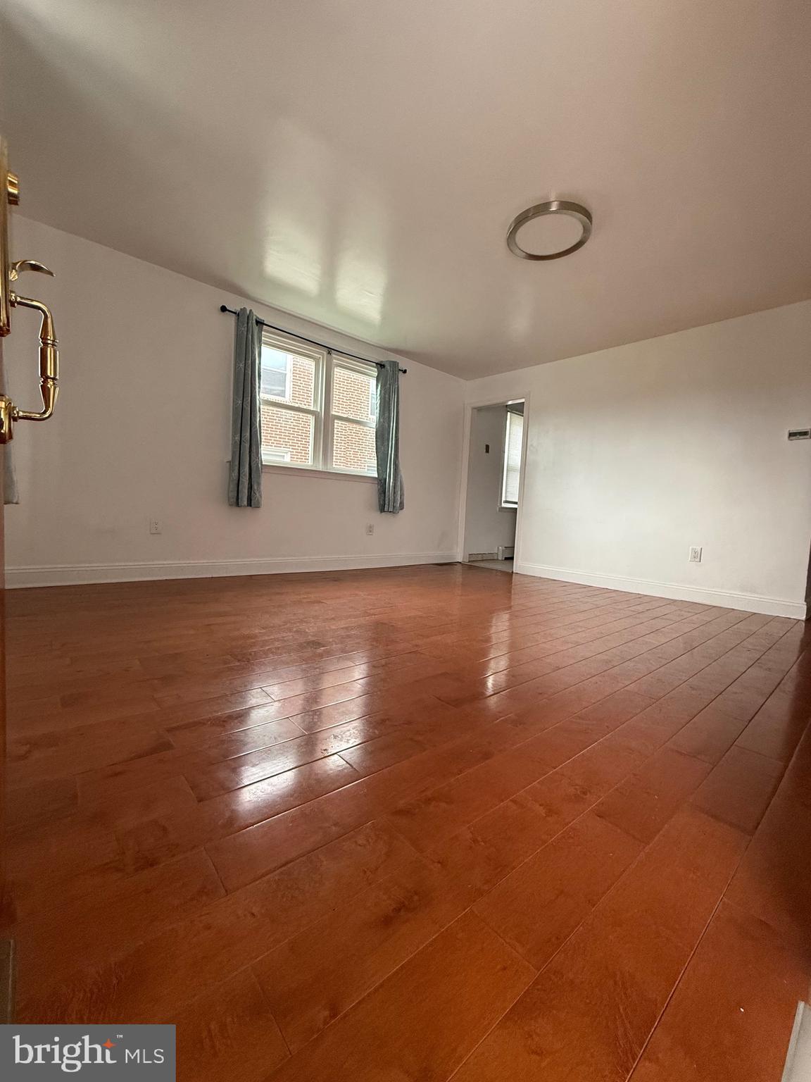 3220 Guilford Street Philadelphia, PA 19136 - Photo 4 of 20 an empty room with wooden floor and windows with curtains