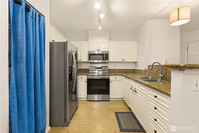 a kitchen with stainless steel appliances granite countertop a stove a sink and white cabinets