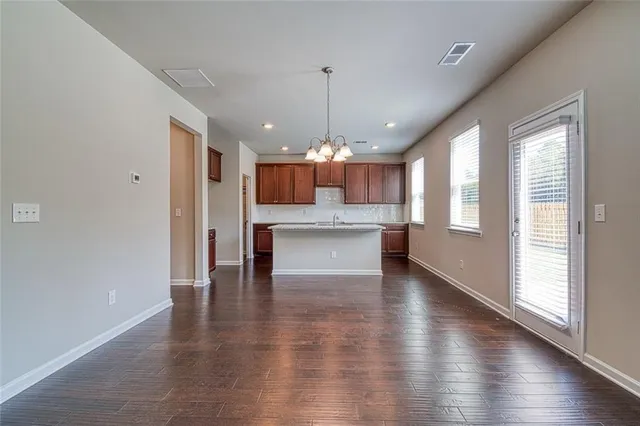 a view of an empty room with kitchen and window