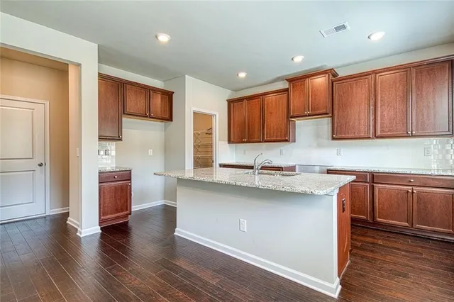 a kitchen with stainless steel appliances granite countertop wooden cabinets a sink a stove a refrigerator and dishwasher with wooden floor