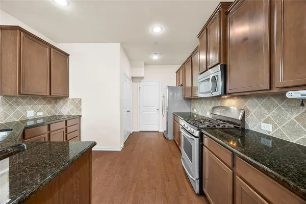 a kitchen with stainless steel appliances granite countertop a sink a stove and a wooden cabinets