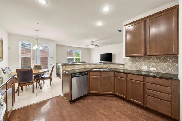 a large kitchen with cabinets chairs and wooden floor