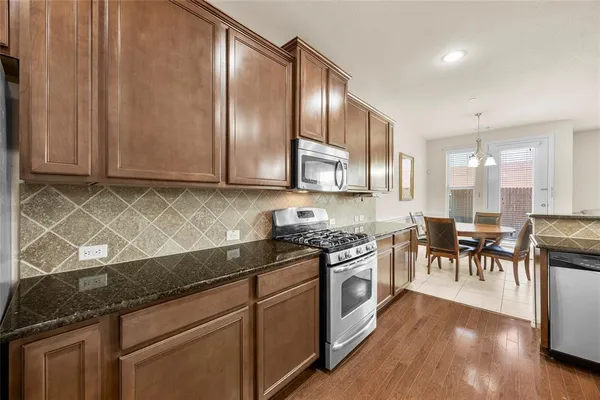 a kitchen with stainless steel appliances granite countertop wooden cabinets a stove top oven a sink and dishwasher