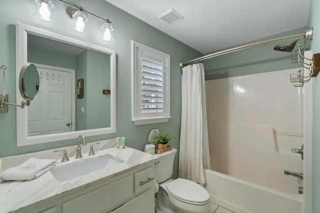 a bathroom with a granite countertop sink toilet a shower a mirror and a bathtub