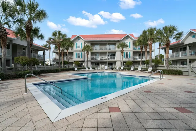 a view of a swimming pool with a lounge chairs in front of a house