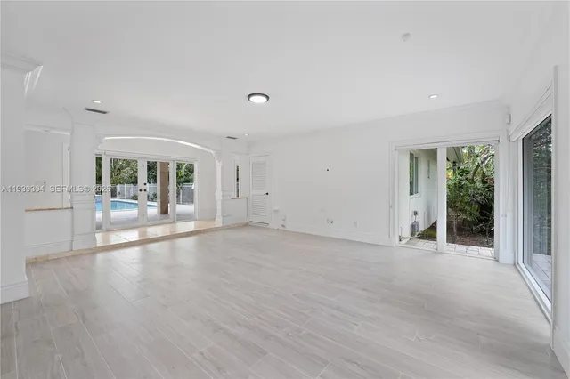 a view of an empty room with window and wooden floor
