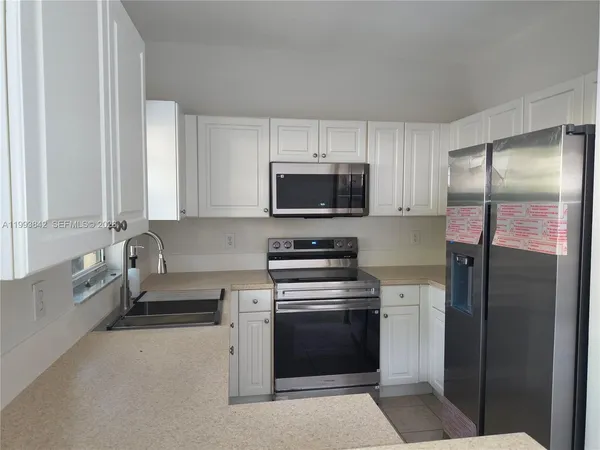 a kitchen with white cabinets and stainless steel appliances