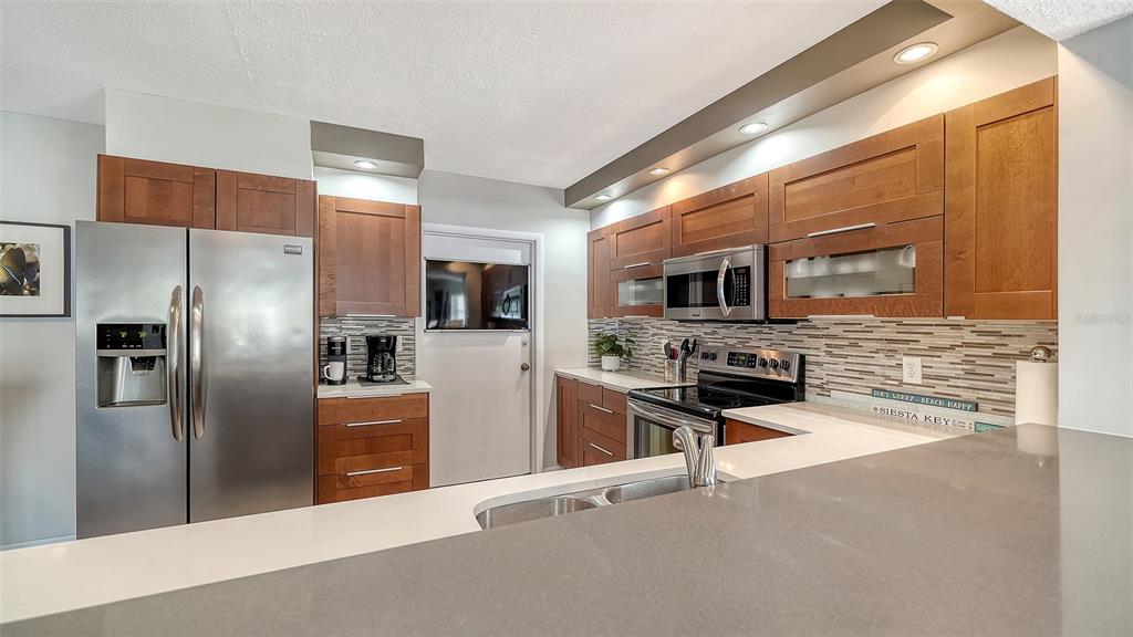 225 Hour Glass Way, Unit 202 Sarasota, FL 34242 - Photo 24 of 68 a kitchen with stainless steel appliances wooden cabinets a refrigerator and a stove