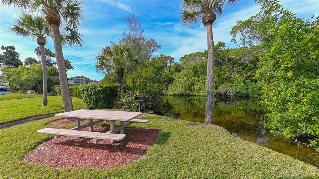 225 Hour Glass Way, Unit 202 Sarasota, FL 34242 - Photo 38 of 68 a view of a backyard with table and chairs potted plants and palm trees