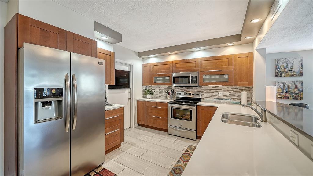 225 Hour Glass Way, Unit 202 Sarasota, FL 34242 - Photo 9 of 68 a large kitchen with stainless steel appliances granite countertop a refrigerator and a stove top oven