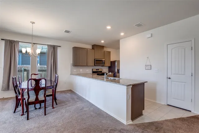 a kitchen with stainless steel appliances kitchen island granite countertop a table and chairs in it