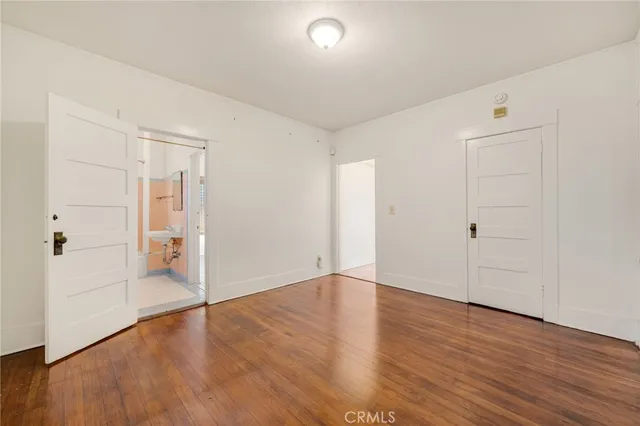 an empty room with wooden floor & windows and bathroom