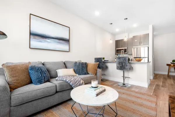 a living room with furniture kitchen view and a wooden floor