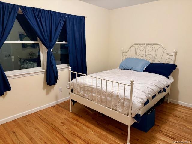 120 East 6th Road Queens, NY 11693 - Photo 10 of 22 a bedroom with a bed a mirror and wooden floor