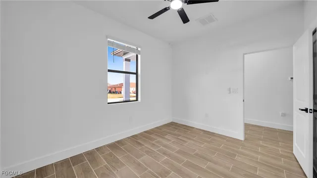 an empty room with a window and ceiling fan