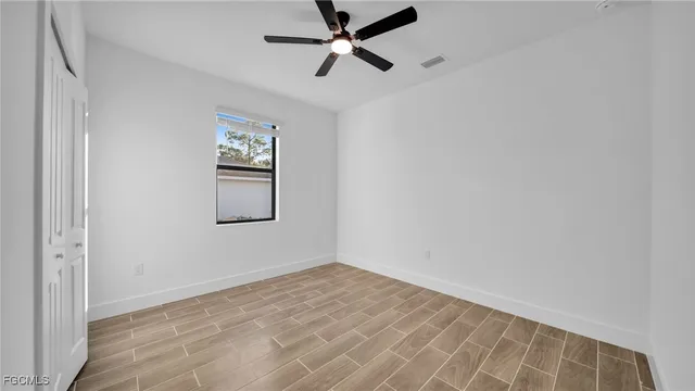 a view of empty room with wooden floor and fan