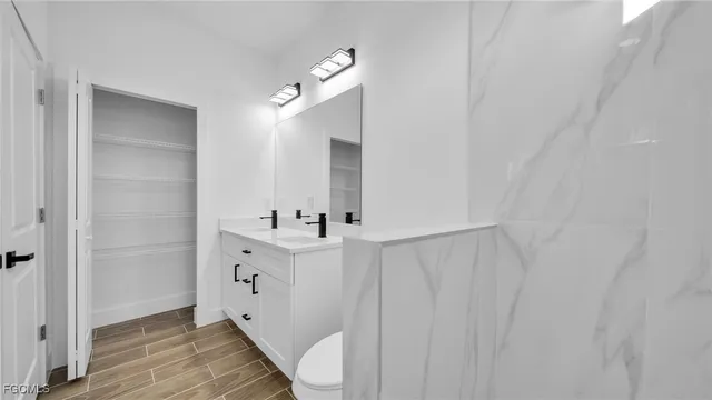 a bathroom with a toilet a sink a mirror and vanity