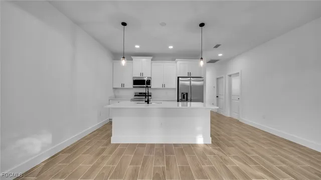 a large white kitchen with wooden floor and a chandelier