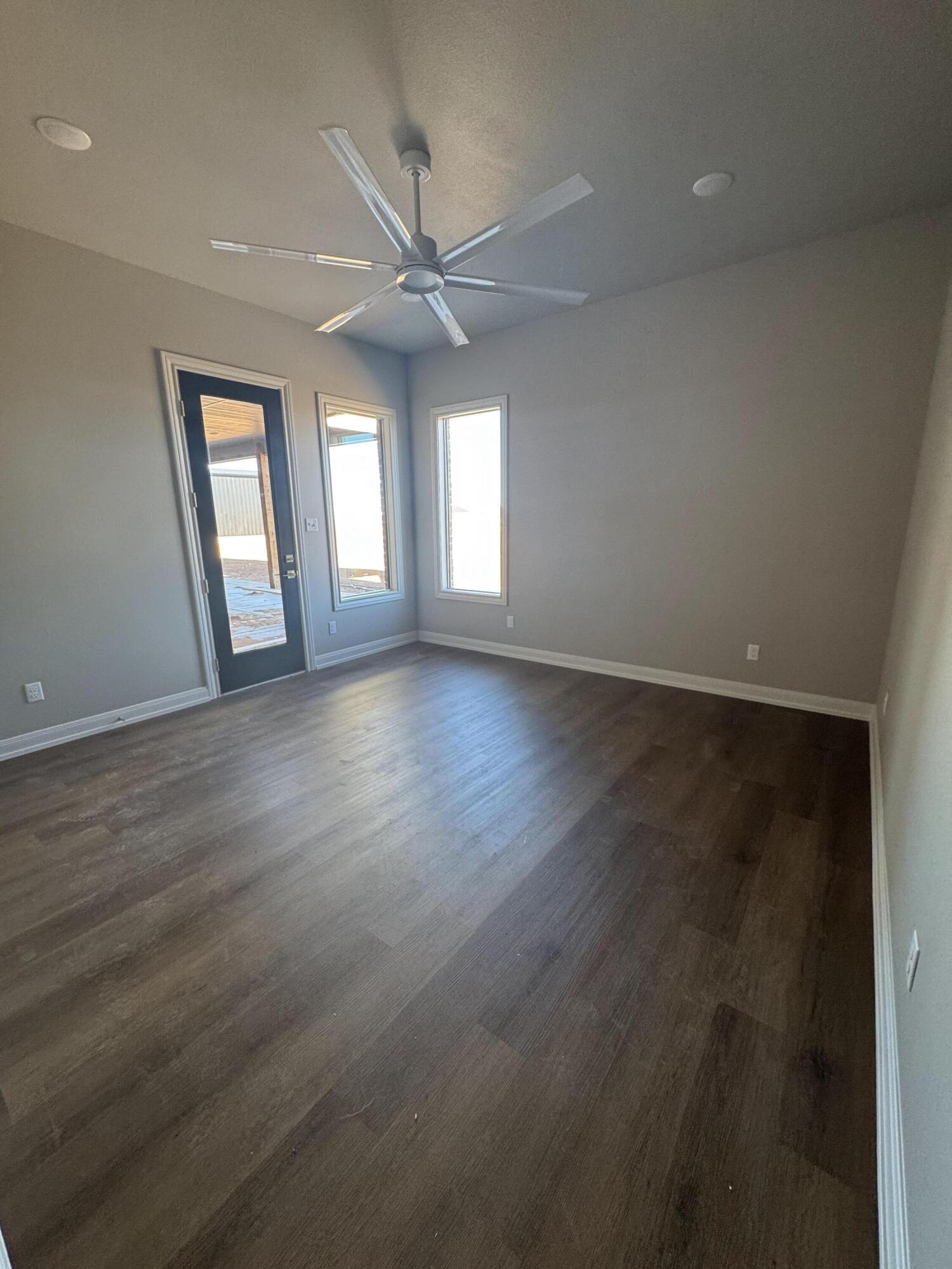 309 Maple New Home, TX 79381 - Photo 20 of 27 an empty room with wooden floor fan and windows
