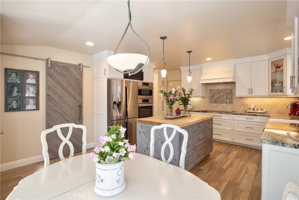 1175 Riverview Drive Fallbrook, CA 92028 - Photo 19 of 57 a kitchen with stainless steel appliances granite countertop a dining table chairs sink and white cabinets