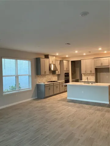 a large kitchen with stainless steel appliances kitchen island a large counter top and a wooden floors