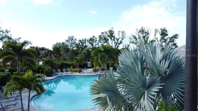 a view of swimming pool with outdoor seating and trees in the background