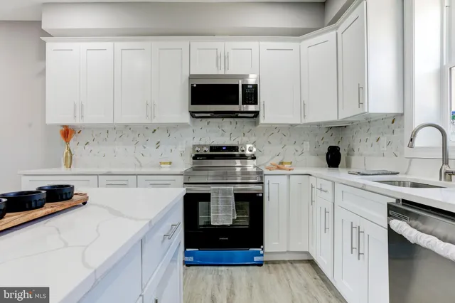 a kitchen with stainless steel appliances granite countertop a stove a sink and a microwave