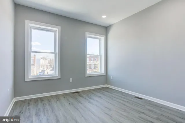 an empty room with wooden floor and windows