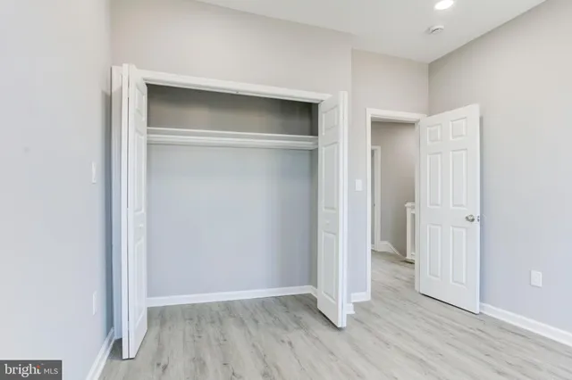 a view of an empty room with wooden floor and closet