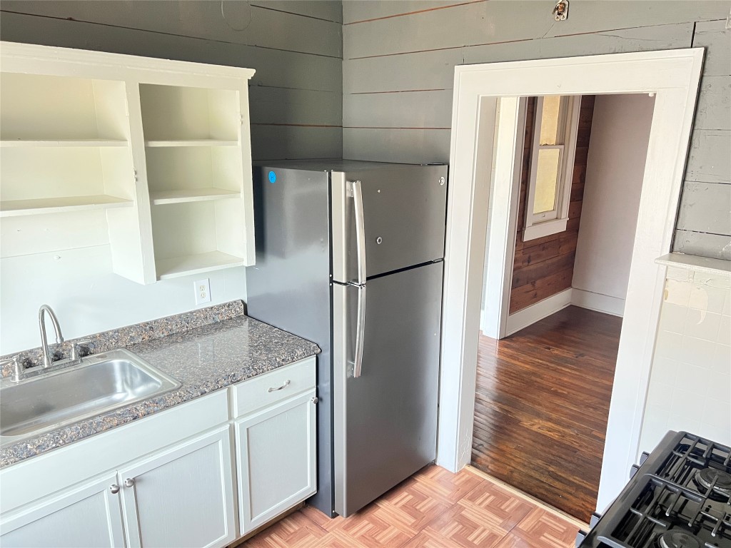 703 West 11th Street, Unit 5 Austin, TX 78701 - Photo 1 of 12 Kitchen with freestanding refrigerator, parquet floors, wood walls, open shelves, and gas range oven