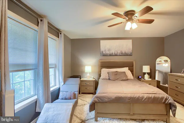 a bedroom with a bed painting on wall and a large window