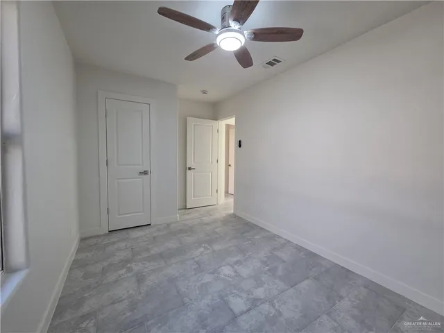 an empty room with closet and a chandelier fan