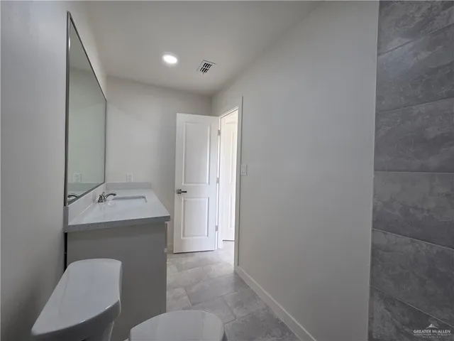 a hall with a sink and mirror with toilet