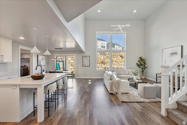 882 Spring Dew Lane Lehi, UT 84048 - Photo 9 of 46 Living room with dark wood-style flooring, recessed lighting, healthy amount of natural light, and a high ceiling
