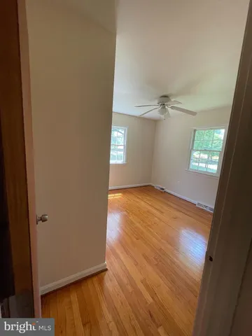an empty room with wooden floor cabinet and windows
