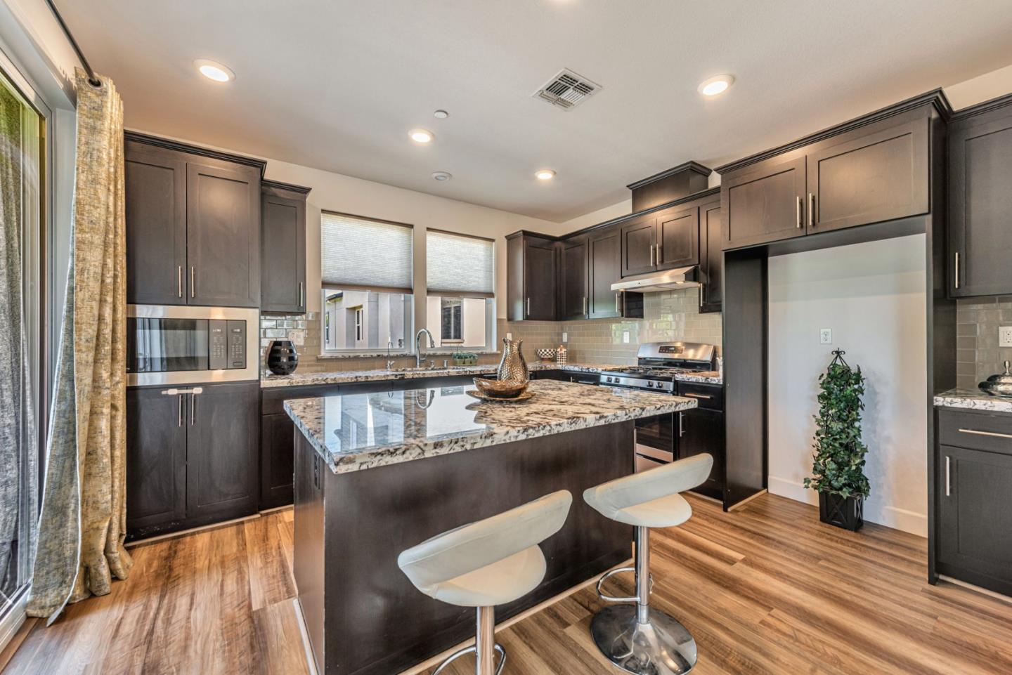 96 Zenith Common Fremont, CA 94539 - Photo 11 of 53 a kitchen with kitchen island a stove a refrigerator and a dining table with wooden floor