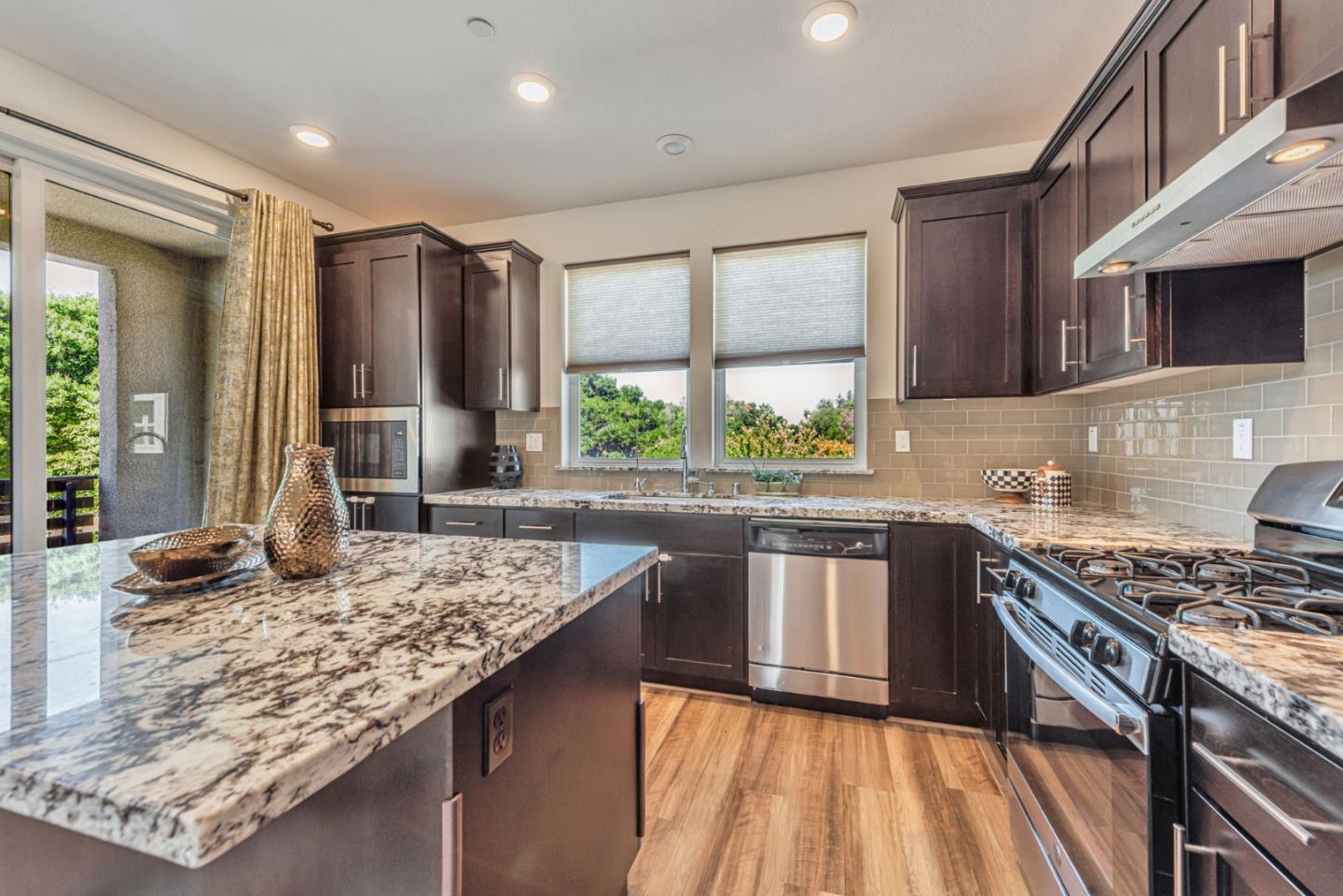 96 Zenith Common Fremont, CA 94539 - Photo 13 of 53 a kitchen with kitchen island granite countertop a stove and a sink