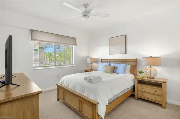 a bedroom with a bed and a flat tv screen on dresser