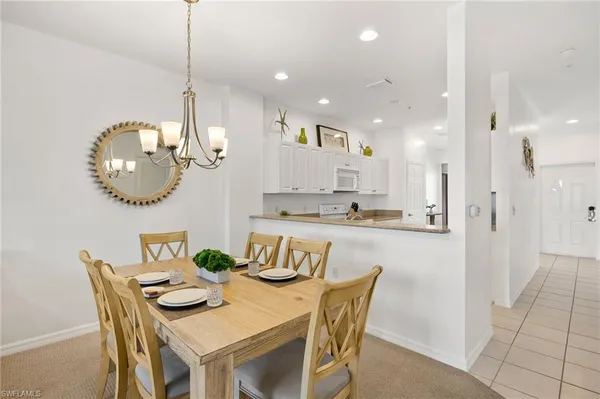 a kitchen with stainless steel appliances granite countertop a dining table chairs and a refrigerator