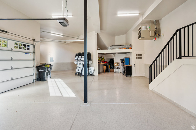1141 South Oak Leaf Lane Springville, UT 84663 - Photo 111 of 147 MAIN pacious garage featuring a light-colored epoxy floor, overhead lighting, a white panel garage door with windows, a white interior door, and a black metal handrail ascending a staircase