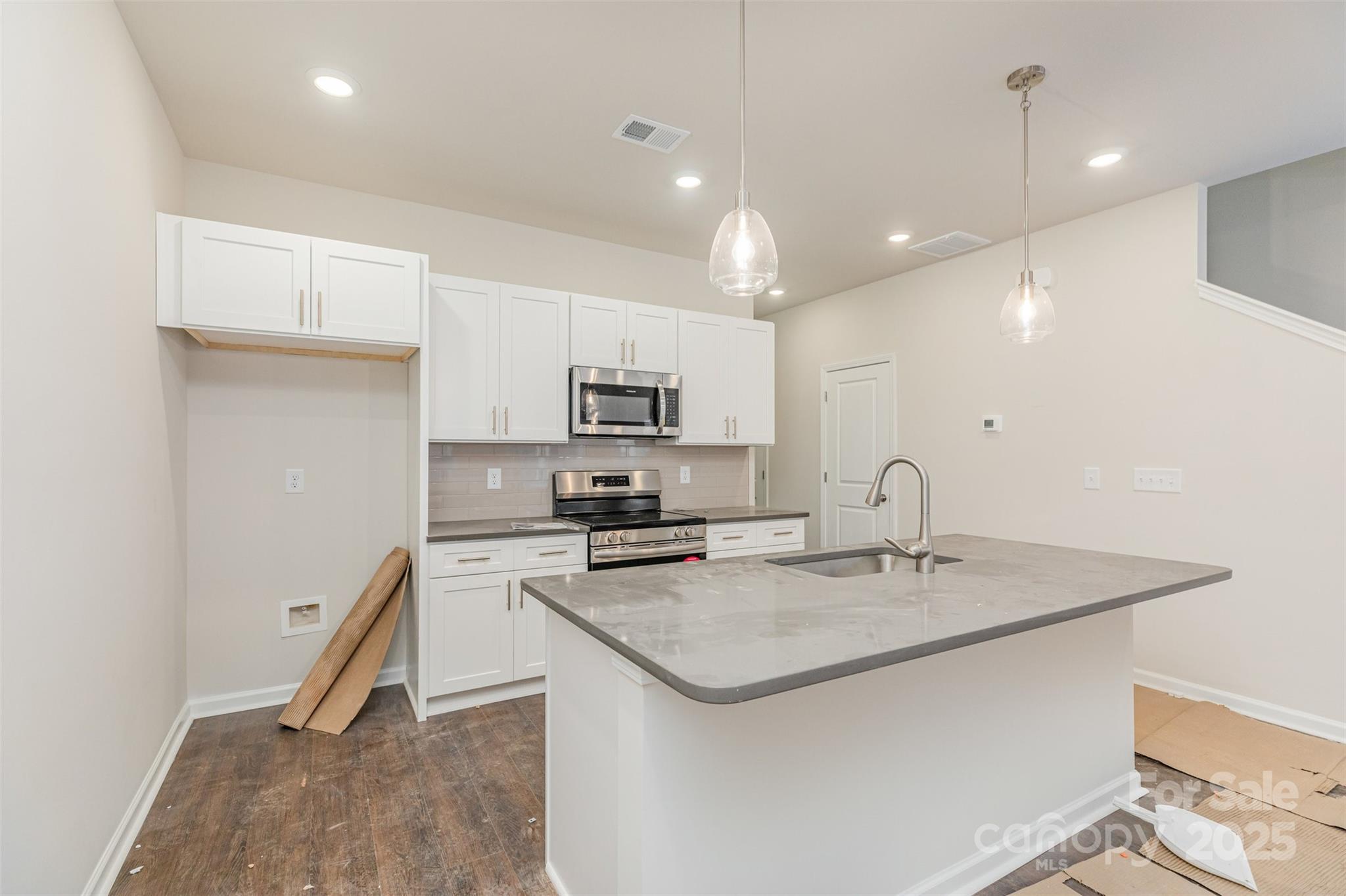 7304 Boswell Road Charlotte, NC 28215 - Photo 11 of 30 a kitchen with a sink a center island a stove a dining table and chairs