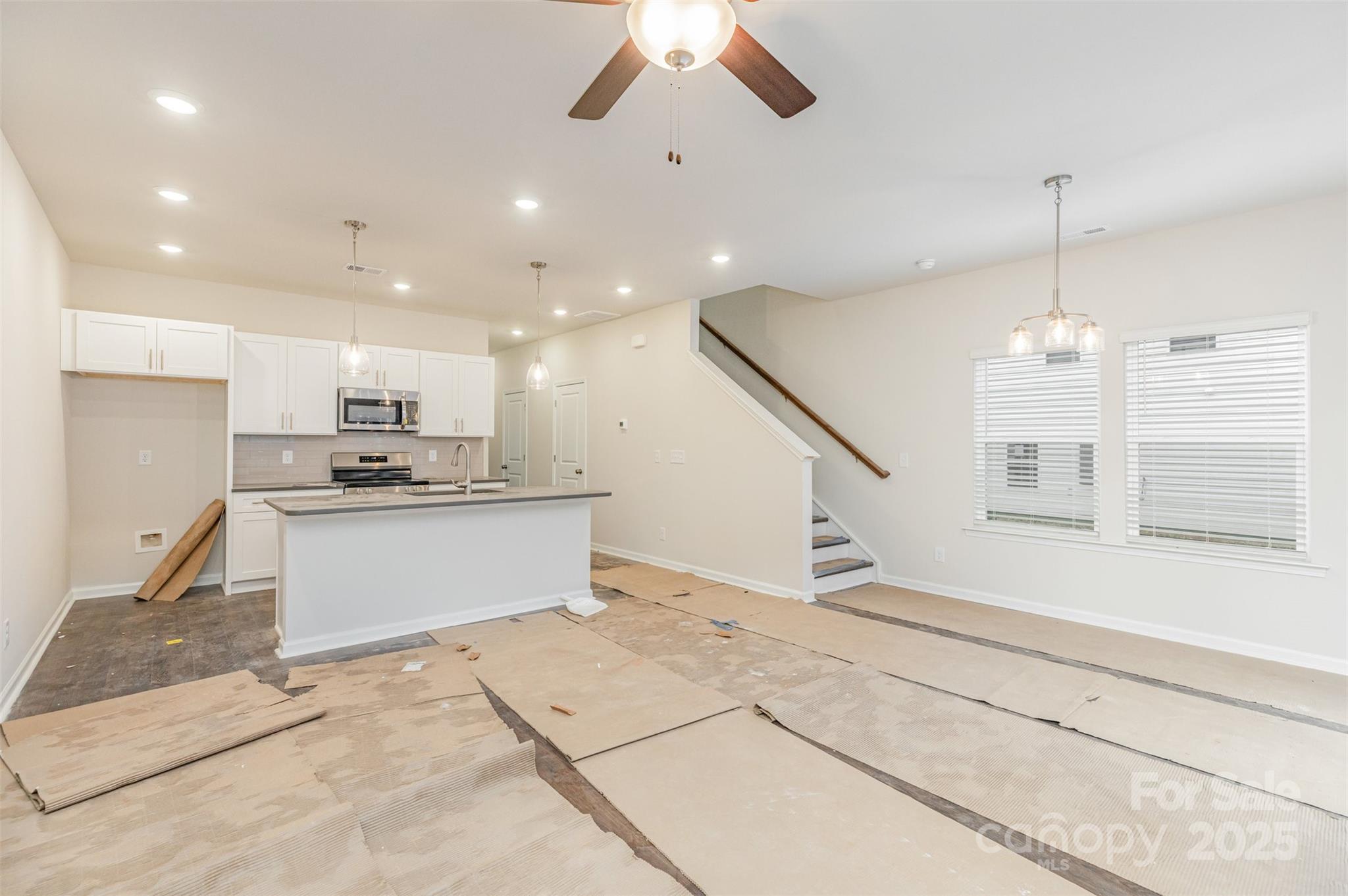 7304 Boswell Road Charlotte, NC 28215 - Photo 6 of 30 a large white kitchen with kitchen island a sink stainless steel appliances and a chandelier