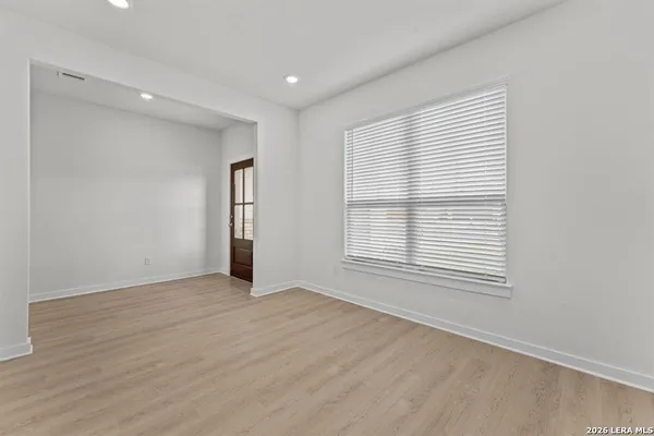 a view of an empty room with wooden floor and a window