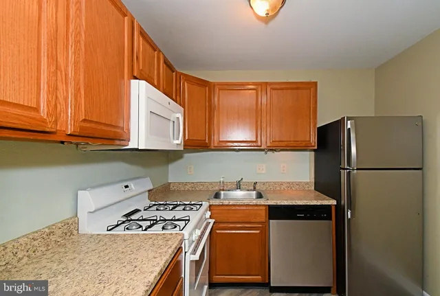 a kitchen with stainless steel appliances granite countertop a refrigerator a stove a sink and a cabinets