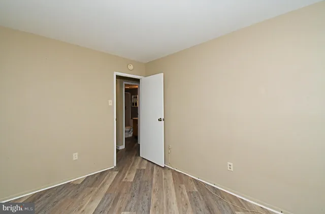 a view of an empty room with wooden floor and closet